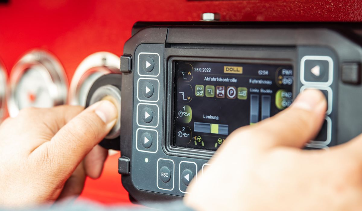 Hands operating the 7-inch colour display of the DOLL control trailer management system.