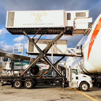 DOLL Catering X-Cat L highloader next to a plane at the airport