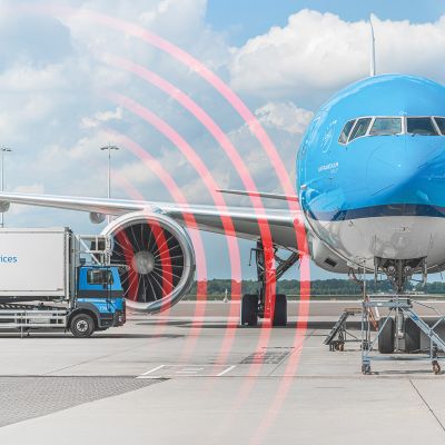 KLM airplane at an airport gate with a catering truck beside it, showing red radar waves indicating proximity detection.