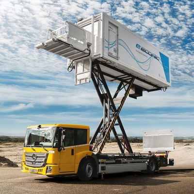 Yellow electric catering truck with elevated platform, set against a scenic blue sky and open landscape.