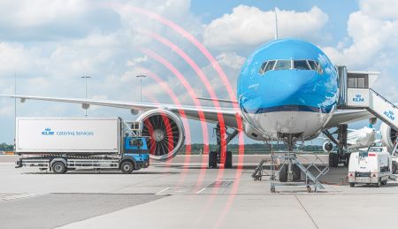 KLM airplane at an airport gate with a catering truck beside it, showing red radar waves indicating proximity detection.