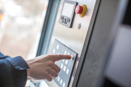 A hand operates the keypad of the DOLL OCS operating and control system