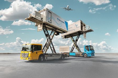 Electric catering trucks with elevated platforms servicing planes, featuring sustainable designs against a clear sky backdrop.